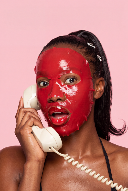 Woman with melanin-rich skin showing a hydrated, healthy glow wearing a Glamquest red hydrogel Korean skincare mask